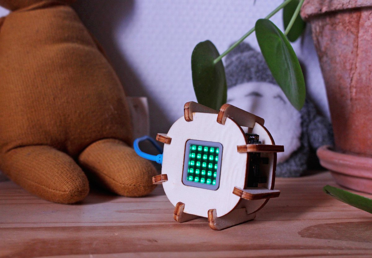 An image of a CO2 sensor with a laser cut wooden case sitting on a wooden table. A 5x5 LED matrix is mounted to the sensor. In this image all LEDs in the matrix are green.